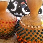 Dois agbês artesanais decorados com contas coloridas.