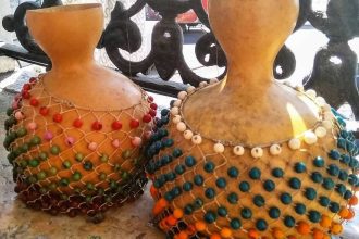 Dois agbês artesanais decorados com contas coloridas.