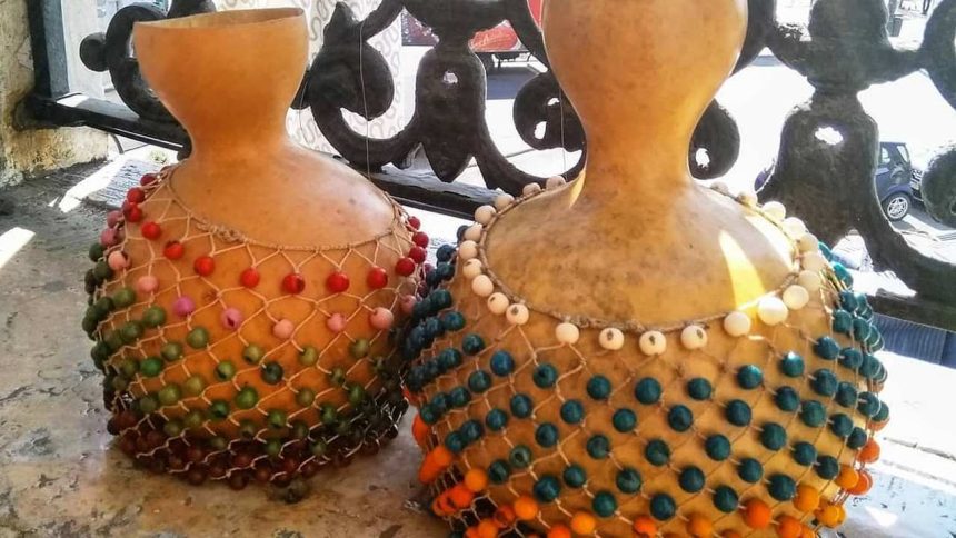 Dois agbês artesanais decorados com contas coloridas.