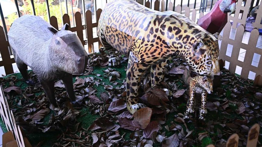 Esculturas de animais feitas de papelão, incluindo uma onça-pintada com um filhote, uma capivara e um papagaio.