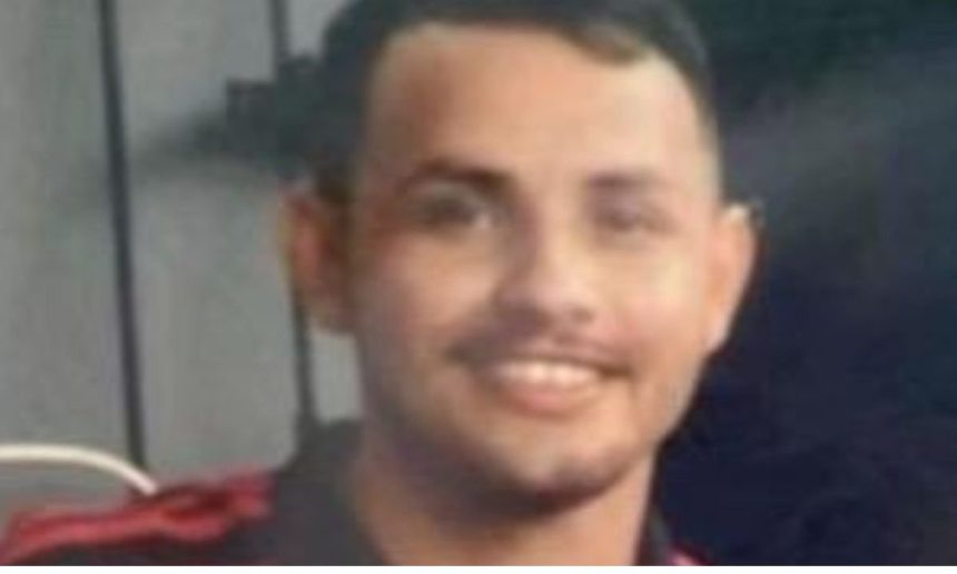 Fabrício, 24 anos, vítima de assassinato, com camisa preta e detalhe vermelho.
