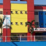 Fachada colorida de escola em Manaus, com letreiro da EJA e árvores.