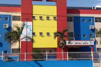 Fachada colorida de escola em Manaus, com letreiro da EJA e árvores.