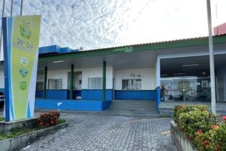 Fachada da 26º DIP, com placa e vegetação.