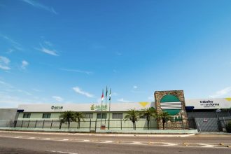 Fachada da AFEAM, prédio com bandeiras e letreiros sob céu azul