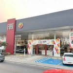 Fachada da concessionária Fiat Murano, com carros e anúncios de ofertas.