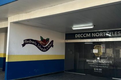 Fachada da DECCM Norte/Leste, delegacia especializada em crimes contra a mulher, com logo e frase 'Atendimento Integrado à Mulher'.