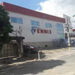Fachada da distribuidora Fennix em Manaus, com carro estacionado e céu nublado.
