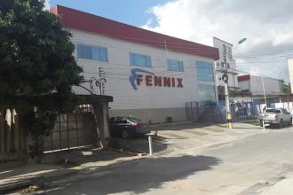 Fachada da distribuidora Fennix em Manaus, com carro estacionado e céu nublado.