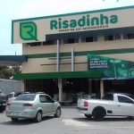 Fachada da loja Risadinha com carros estacionados. Emblema da empresa em destaque.