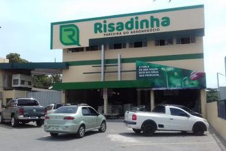 Fachada da loja Risadinha com carros estacionados. Emblema da empresa em destaque.
