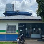 Fachada de delegacia de polícia com antena e moto estacionada