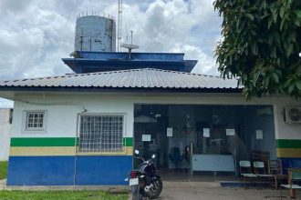 Fachada de delegacia de polícia com antena e moto estacionada