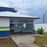 Fachada de delegacia de polícia sob céu nublado.