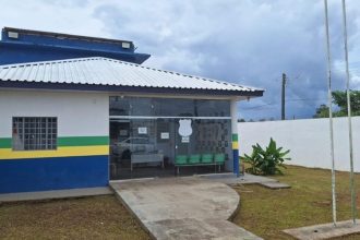 Fachada de delegacia de polícia sob céu nublado.