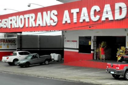 Fachada de loja FRIOTRANS ATACADO, com veículos estacionados em frente.