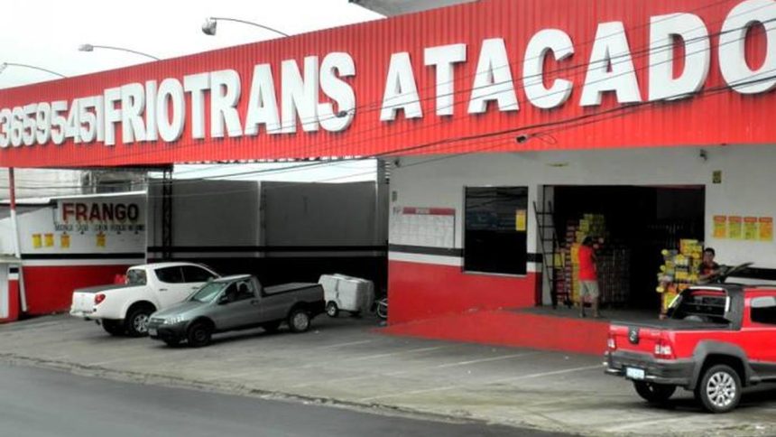 Fachada de loja FRIOTRANS ATACADO, com veículos estacionados em frente.