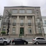 Fachada do Colégio Santa Doroteia, prédio histórico com colunas e carros estacionados em frente.