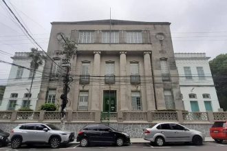 Fachada do Colégio Santa Doroteia, prédio histórico com colunas e carros estacionados em frente.