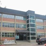 Fachada do edifício da iTeam, em Manaus, com arquitetura moderna, janelas amplas e um elevador envidraçado.