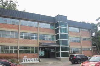 Fachada do edifício da iTeam, em Manaus, com arquitetura moderna, janelas amplas e um elevador envidraçado.