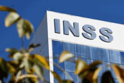 Fachada do prédio do INSS com o logotipo em destaque e folhagens em primeiro plano.