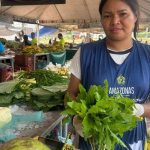 Feira em Manaus: Vendedora com verduras frescas em meio a outros produtos.