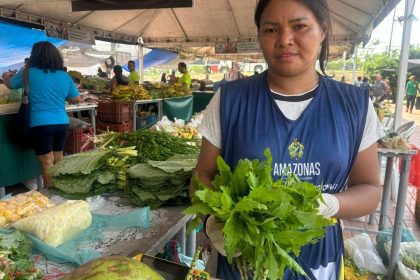 Feira em Manaus: Vendedora com verduras frescas em meio a outros produtos.