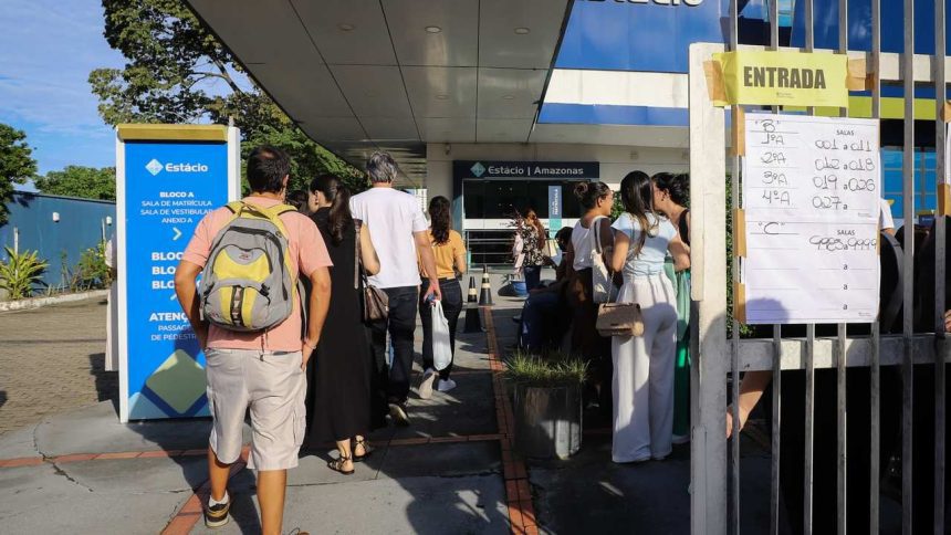 Fila de pessoas em frente ร  entrada da Estรกcio Amazonas, com avisos de salas e blocos.