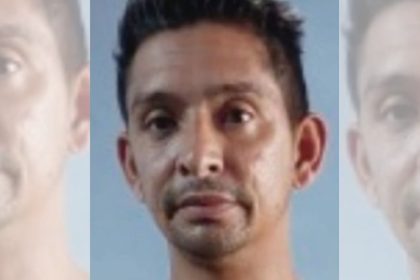 Foto de homem de meia-idade procurado com expressão séria, em fundo azul claro.