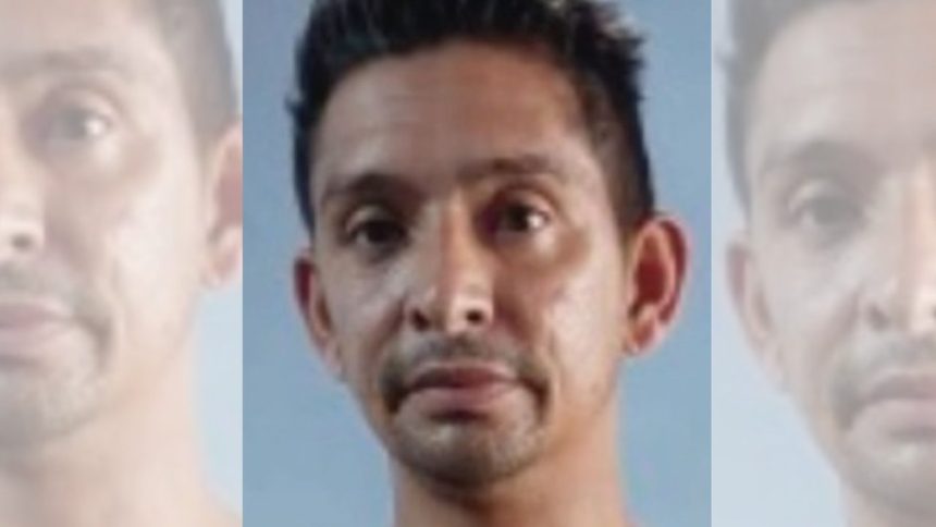 Foto de homem de meia-idade procurado com expressão séria, em fundo azul claro.