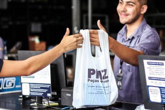 Funcionário entregando sacola com logo PMZ, Peças e Pneus, em loja