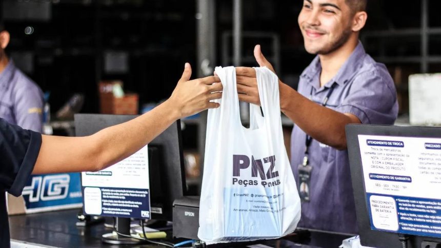 Funcionário entregando sacola com logo PMZ, Peças e Pneus, em loja