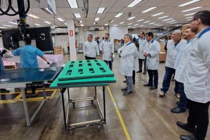 Funcionários em fábrica no Polo Industrial de Manaus, observando processo.