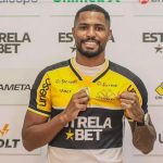 Gabriel Novaes, jogador de futebol, sorrindo e segurando camisa do Criciúma E.C.