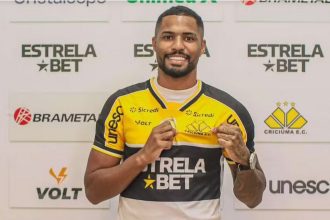 Gabriel Novaes, jogador de futebol, sorrindo e segurando camisa do Criciúma E.C.