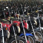 Grande quantidade de motos estacionadas em pátio, diversas cores e modelos.