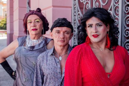 Grupo de pessoas caracterizadas em trajes, possivelmente drag queens, posam para foto.