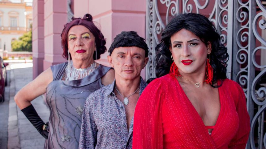 Grupo de pessoas caracterizadas em trajes, possivelmente drag queens, posam para foto.