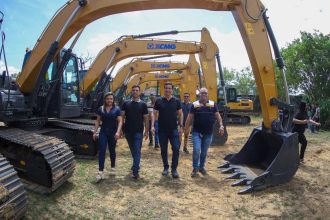 Grupo de pessoas com Sidney Leite em frente a várias escavadeiras XCMG.