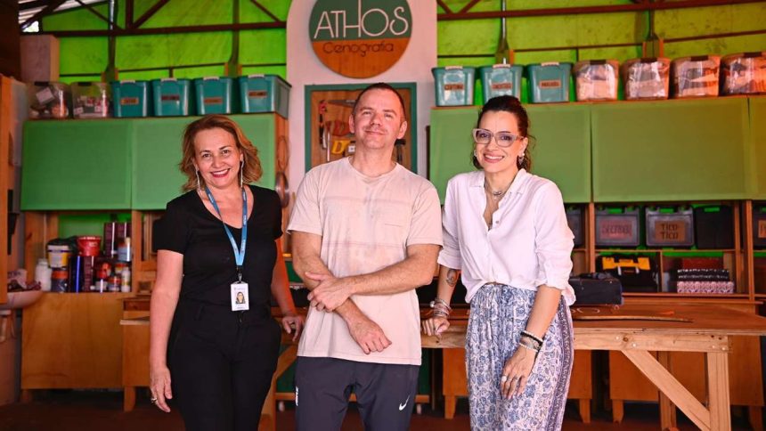Grupo posa em frente ao logotipo da ATHOS Cenografia.