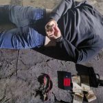 Homem algemado no chão após assalto com arma e celular.