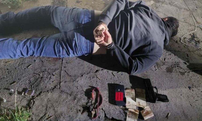 Homem algemado no chão após assalto com arma e celular.