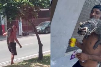 Homem carrega jacaré nos ombros enquanto caminha na rua. Cena inusitada com animal exótico.