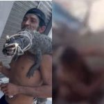 Homem segura jacaré morto nos ombros, com bebida na mão, cena de violência.