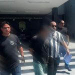 Homem suspeito de homicídio sendo escoltado pela polícia.