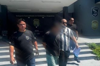 Homem suspeito de homicídio sendo escoltado pela polícia.