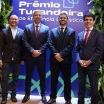 Homens em trajes formais posam para foto em evento de premiação.
