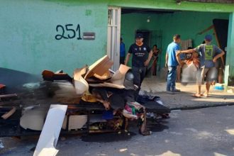 Incêndio em residência no bairro Tancredo Neves, Manaus, com pessoas na frente.