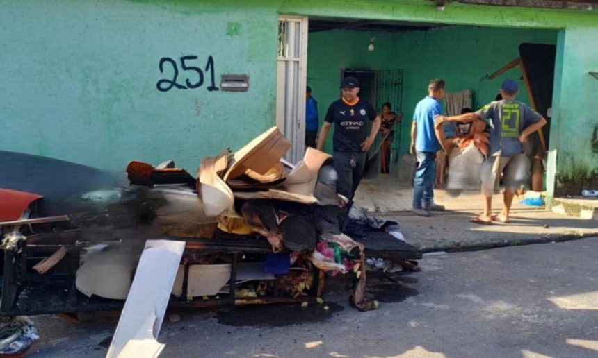 Incêndio em residência no bairro Tancredo Neves, Manaus, com pessoas na frente.